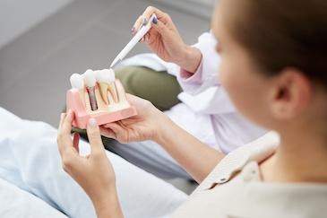 Doctor using diagram to show patient what a dental implant looks like, Downey CA