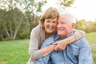 Older man and woman hugging and smiling after denture treatment, Downey CA