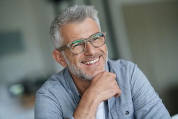 Older man in glasses smiling after dental crown treatment, Downey CA