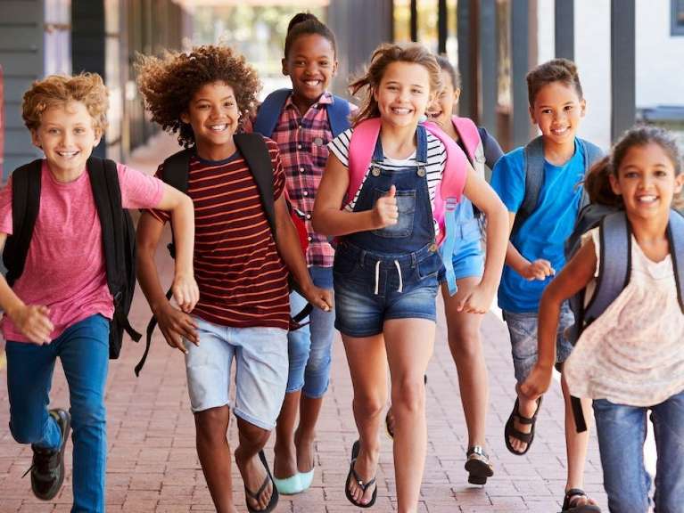 Group of kids with backpacks on running and smiling, downey ca