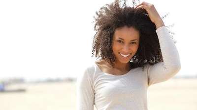 Black woman smiling, playing with hair after getting dental implants, downey ca